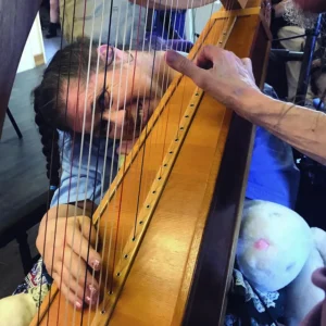 A person playing a harp and smiling