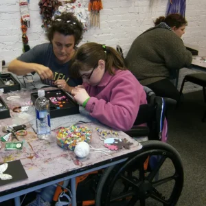 A woman in a wheelchair working with beads